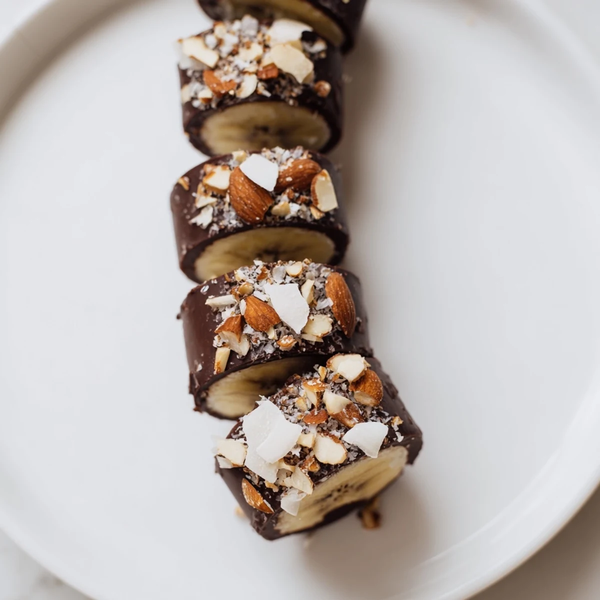 Frozen chocolate-covered banana bites glistening under kitchen lights, perfect for a refreshing treat.