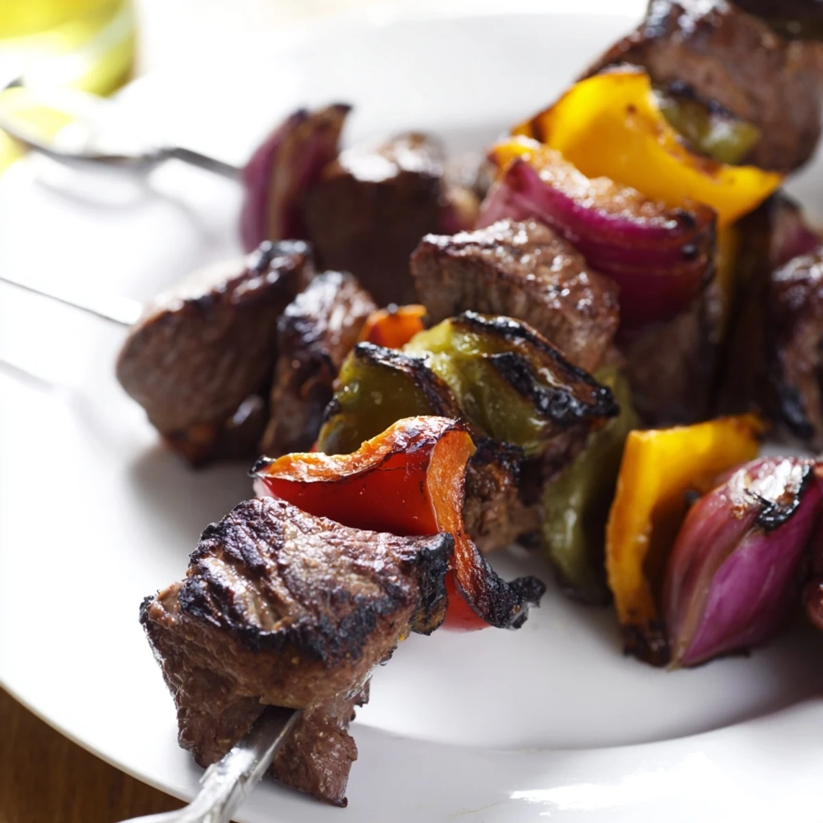 Marinated beef cubes with red onion and peppers on a skewer, served over fluffy white rice.