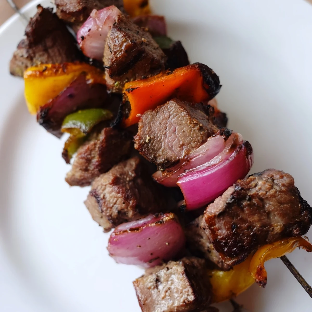 Beef kebabs with bell peppers and red onion, resting on a rustic plate with a lemon wedge.