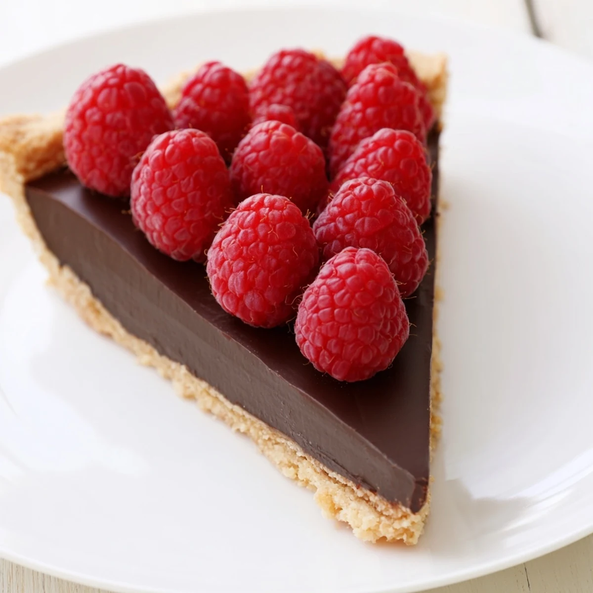 A rustic kitchen scene features a whole Chocolate Raspberry Tart with Pastry ready to be served and enjoyed.