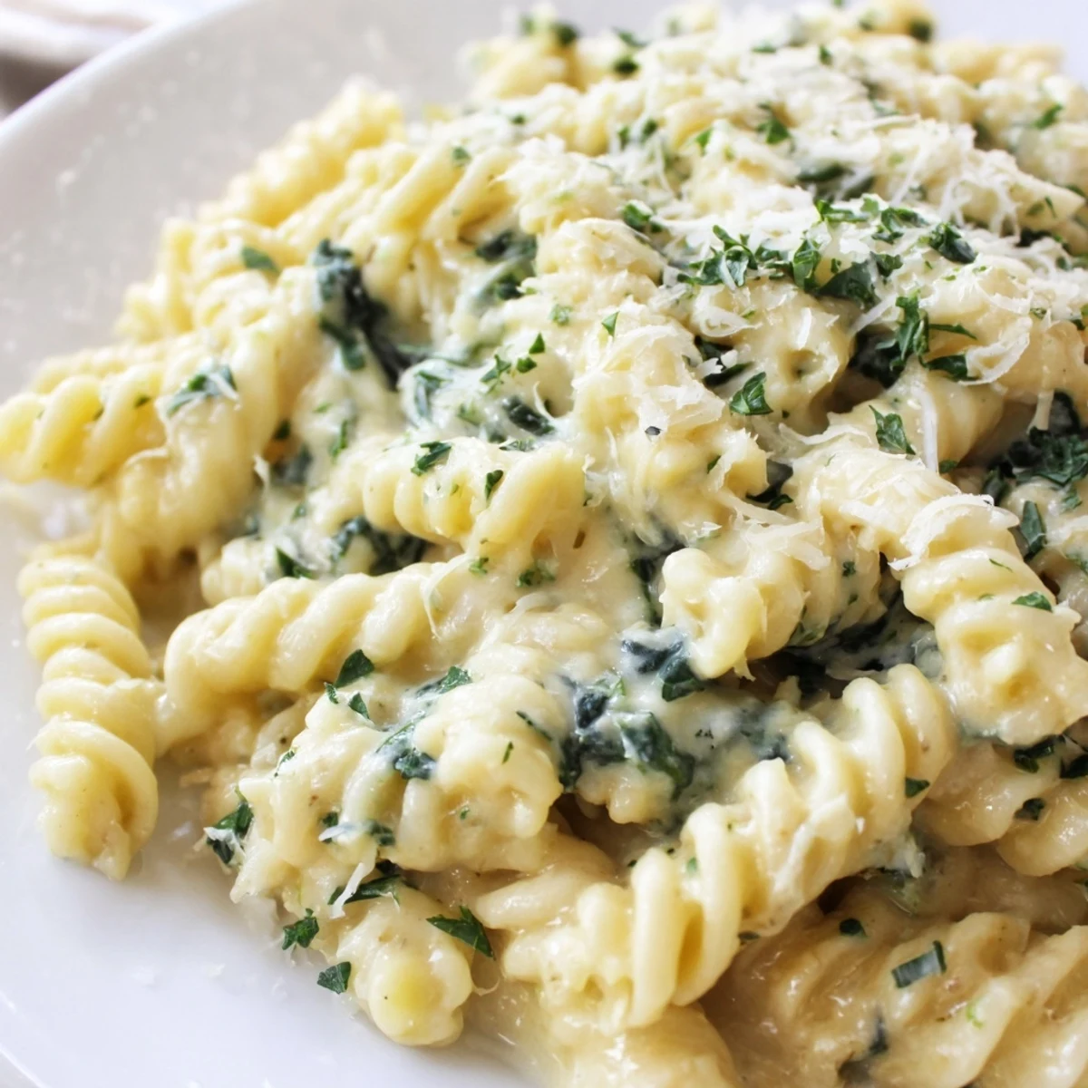 Savory Creamy Spinach and Cheese Pasta served in a warm bowl, garnished with fresh parsley and extra grated Parmesan.