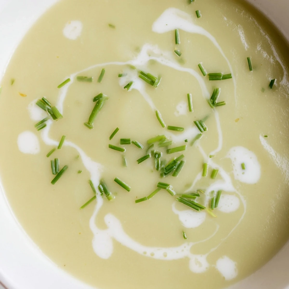 Creamy leek and potato soup in a rustic bowl, garnished with fresh chives and a drizzle of cream.