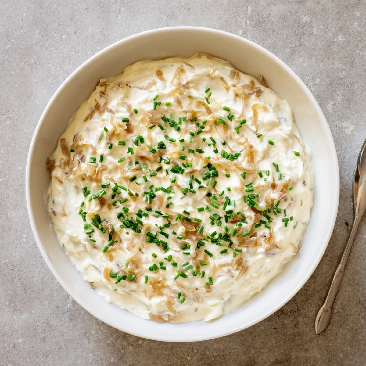 Chilled bowl of creamy Game Day Onion Dip featuring slow-cooked onions and fresh herbs, ideal for game day snacking.