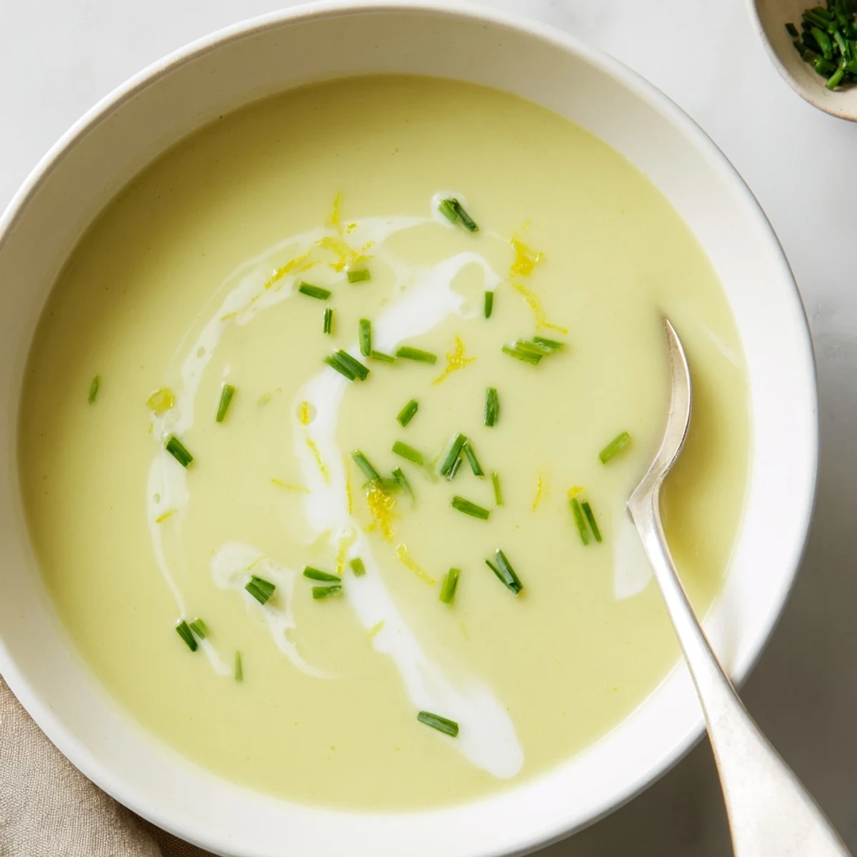 Vibrant green blended Creamy Asparagus Soup with Lemon served hot, garnished with a drizzle of cream and chives. 