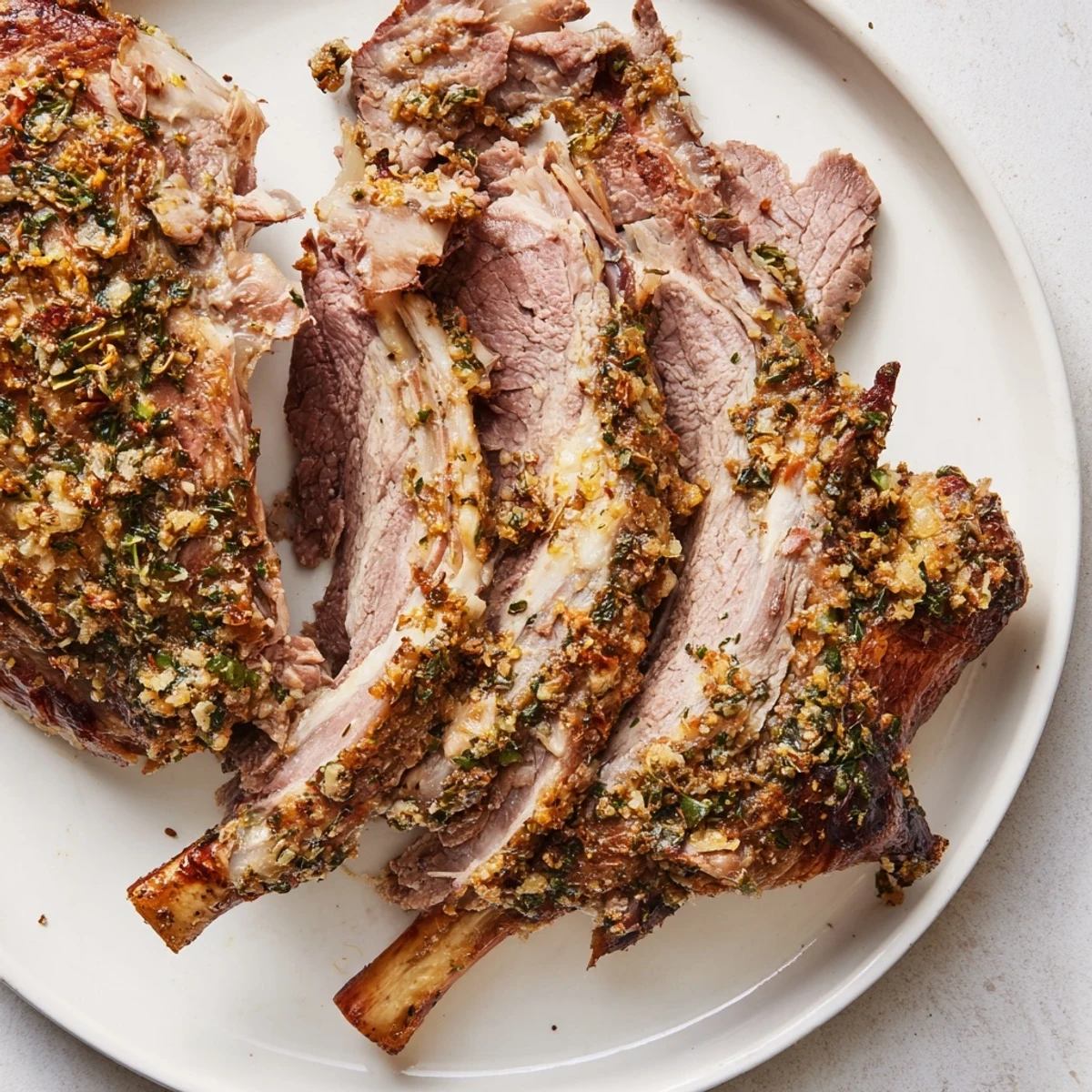 A close-up of Roasted Lamb Shoulder with Fresh Herbs, showcasing the aromatic herb crust and glistening pan juices ready to serve.