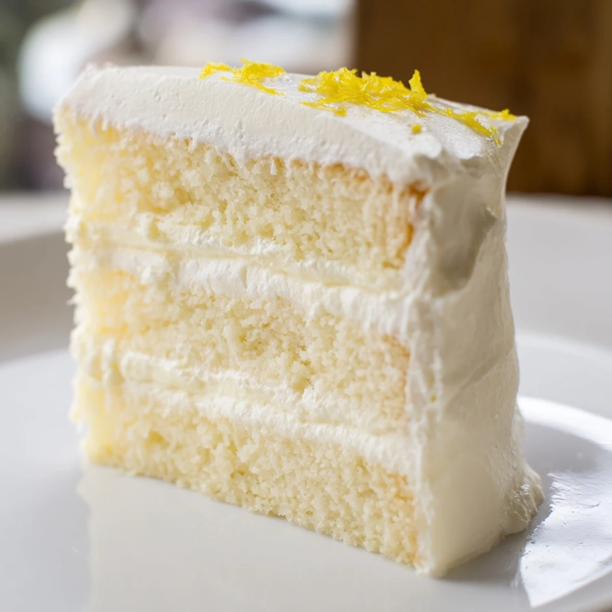 A close-up slice of Limoncello Mascarpone Cake reveals moist sponge soaked in lemon liqueur syrup and mascarpone whipped cream filling.