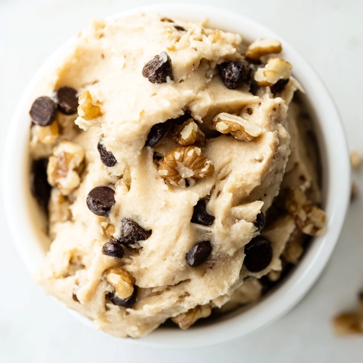 A spoonful of Guilt Free Greek Yogurt Cookie Dough revealing a thick, cookie-dough-like consistency studded with white chocolate chips and chopped walnuts.