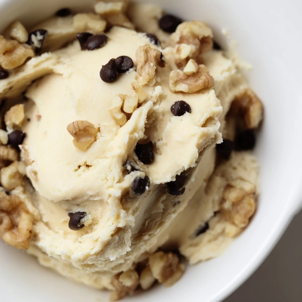 Close-up of Guilt Free Greek Yogurt Cookie Dough in a rustic bowl, showing creamy texture and mini dark chocolate chips, ready to dip with fresh strawberries.