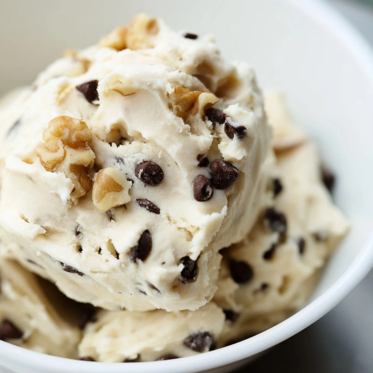 A healthy snack bowl of Guilt Free Greek Yogurt Cookie Dough served with apple slices and pretzels on a marble countertop.