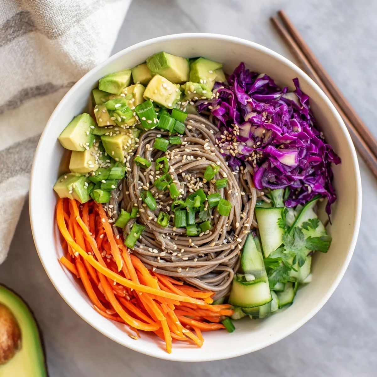 A close-up view shows the sesame avocado and soba noodle salad garnished with green onions and sesame seeds.