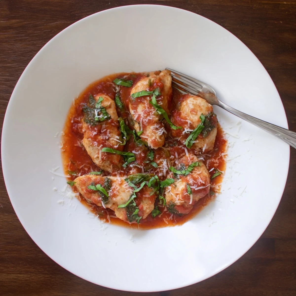 Slow cooker tomato basil chicken with tender chicken breasts in a rich red sauce garnished with fresh basil.