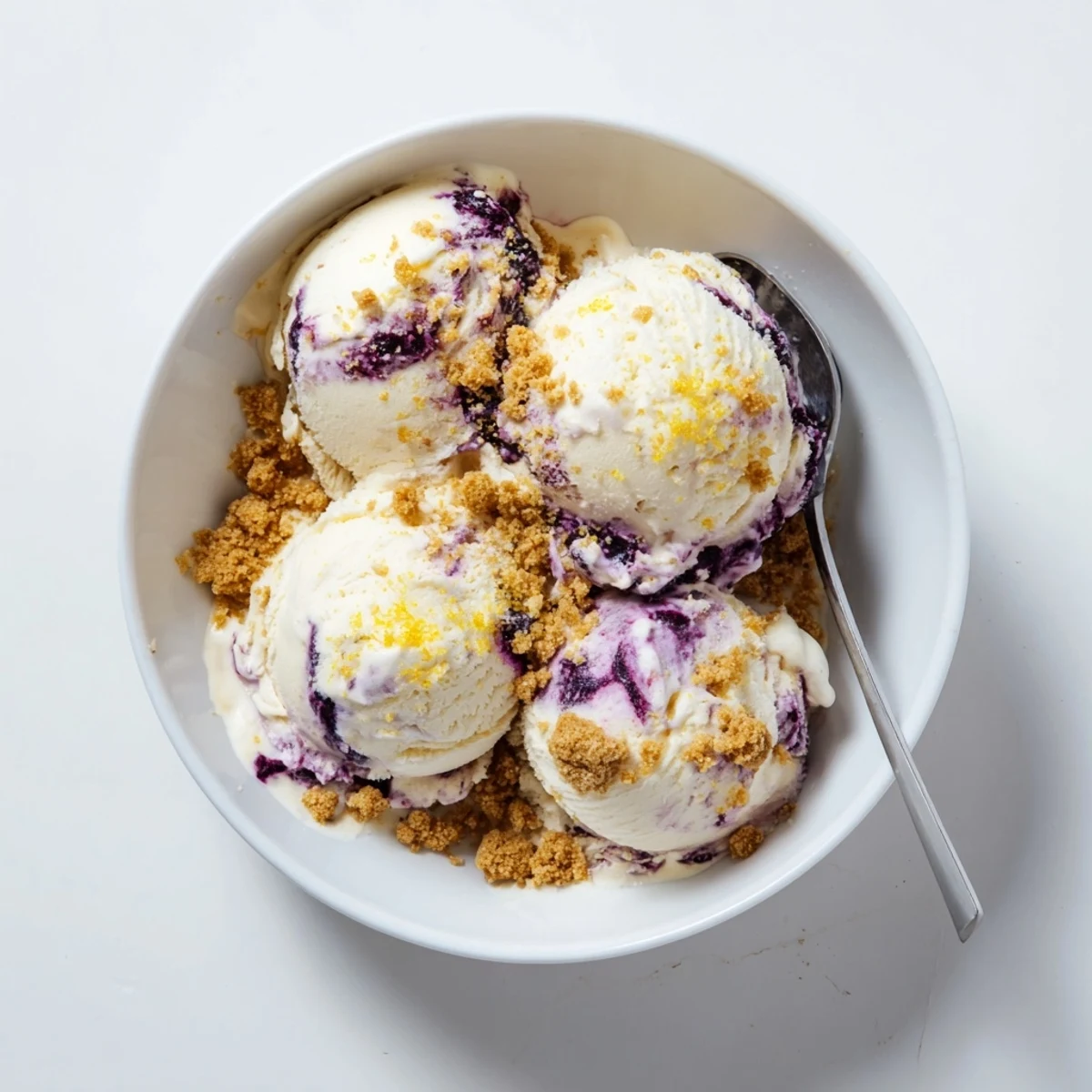 A close-up of homemade Lemon Blueberry Cheesecake Ice Cream featuring tangy lemon zest and rich blueberry compote.