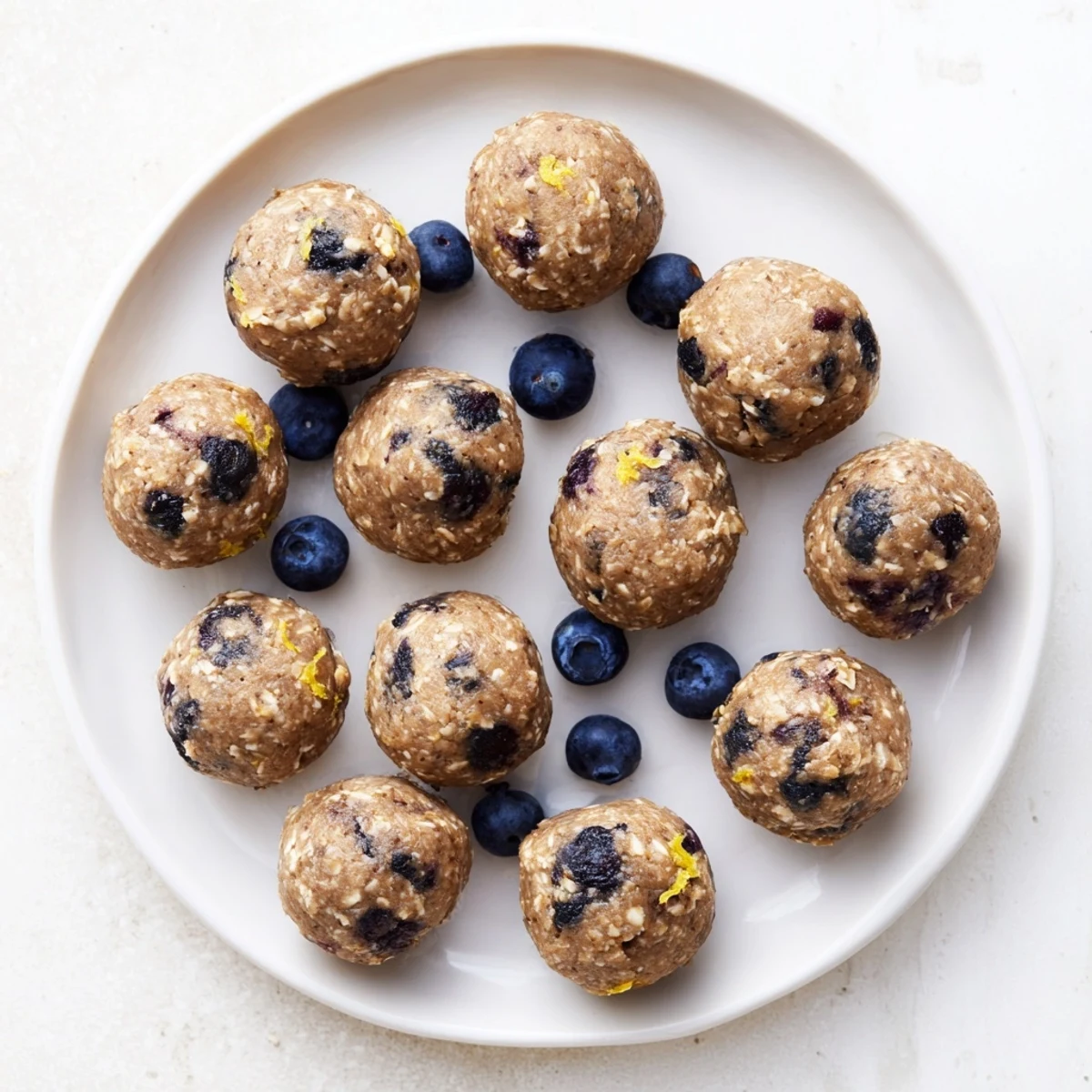 Softened cream cheese and vanilla protein powder mix into a dough for no-bake Blueberry Cheesecake Protein Bites.