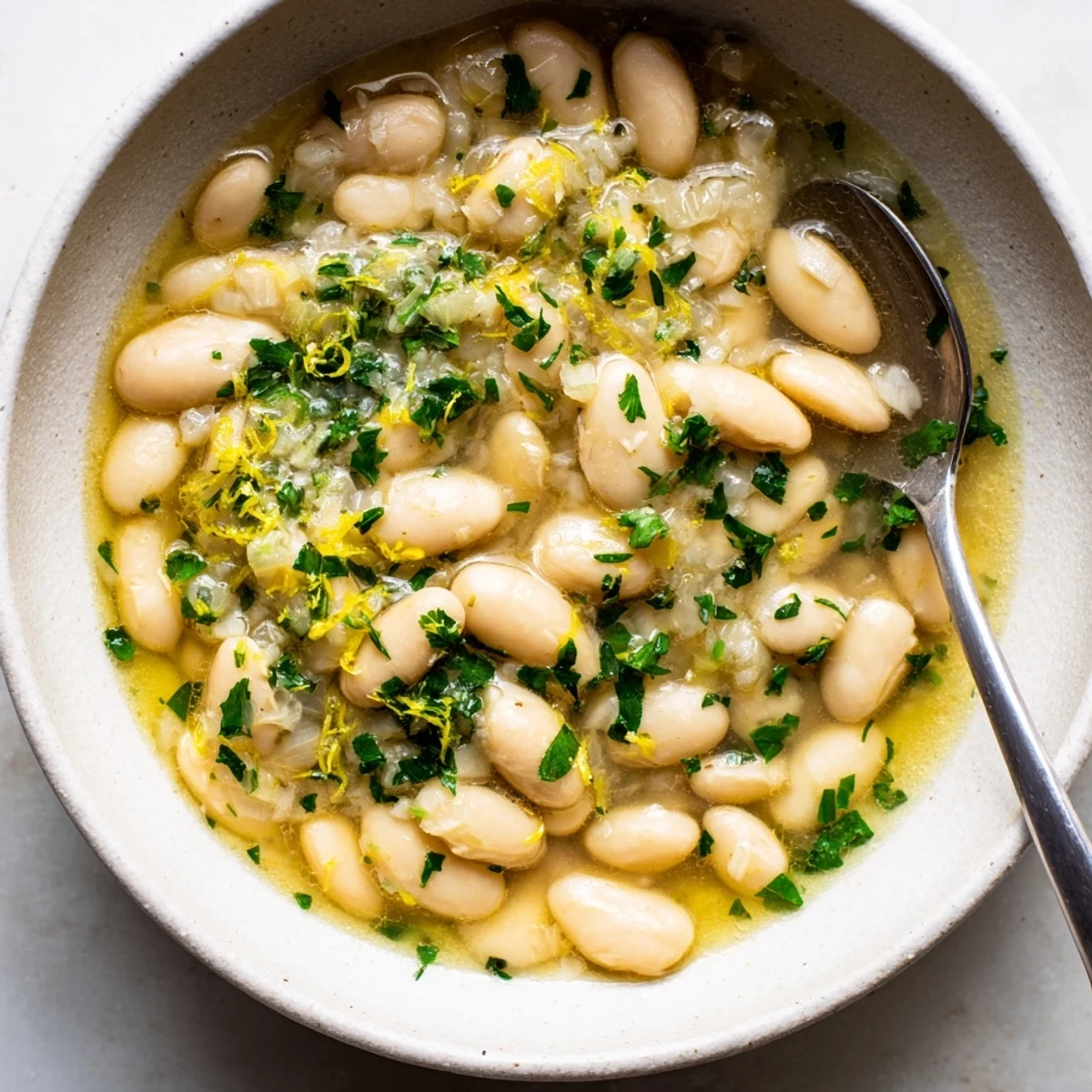 Creamy Miso Butter Brothy Beans simmered in a savory broth beside crusty bread for dipping.