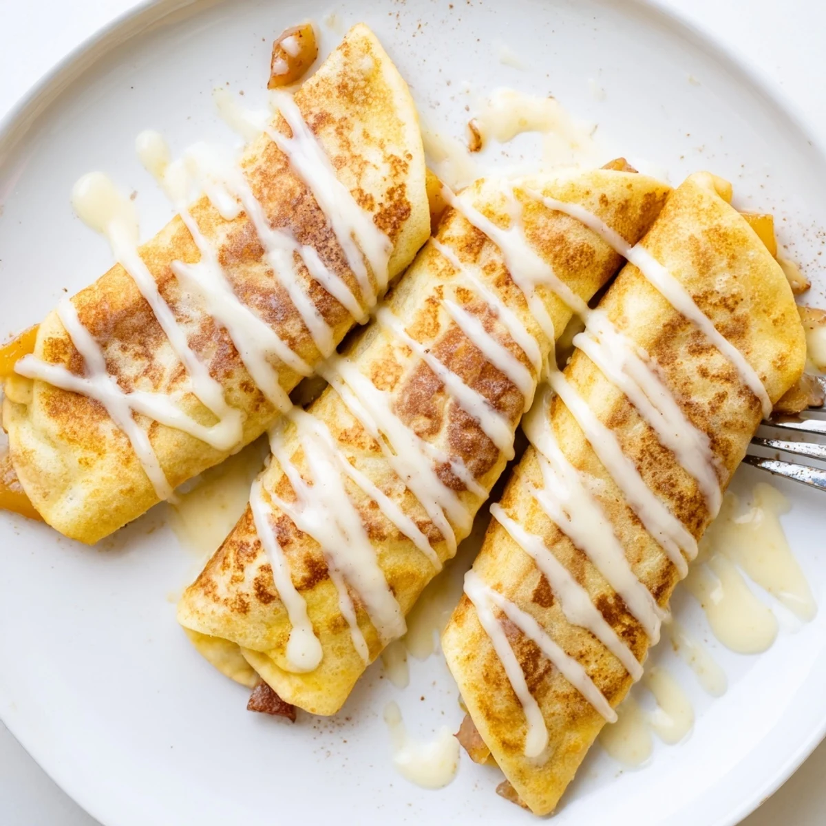 Peach Cobbler Egg rolls, air-fried and golden, rest on a plate with powdered sugar and ripe peaches.