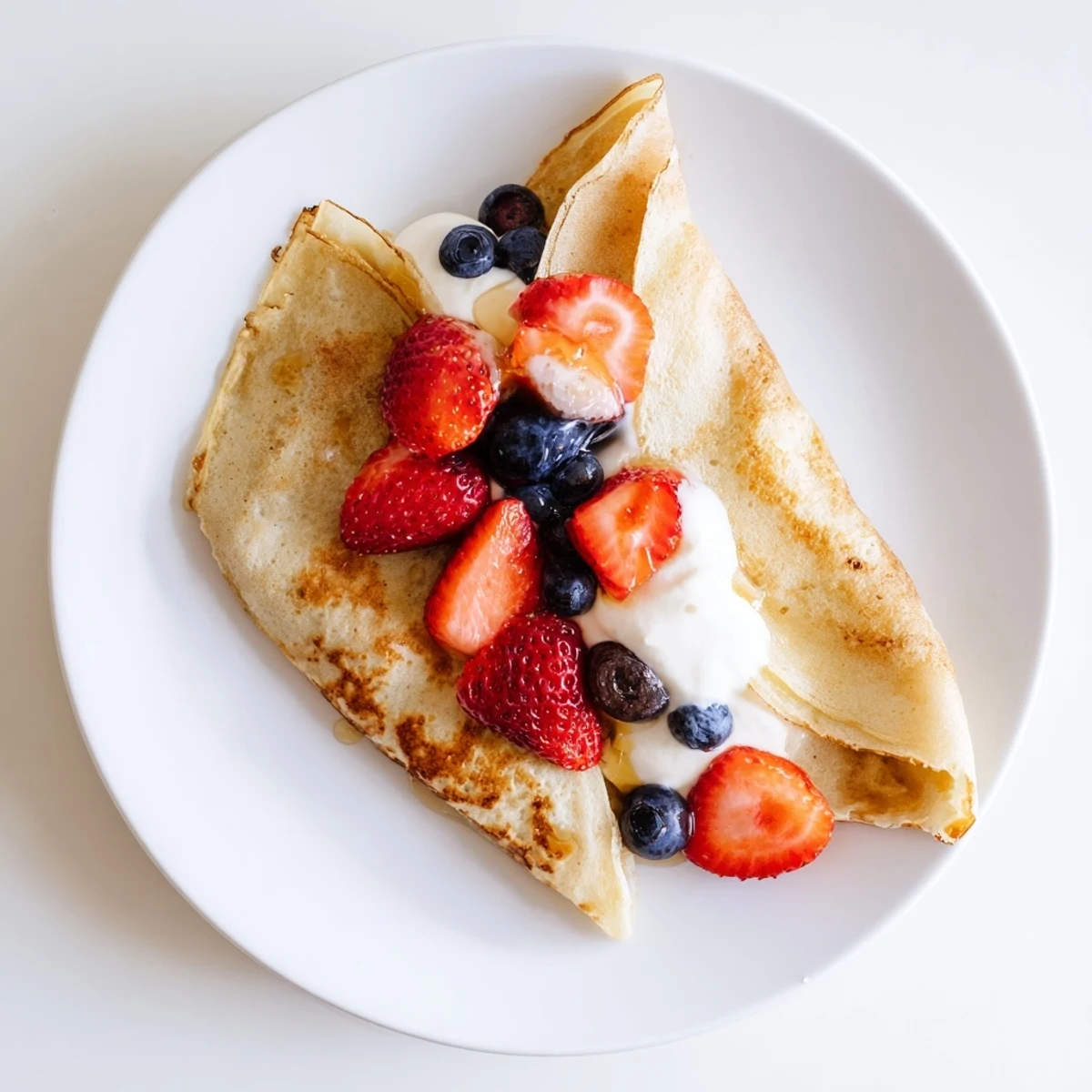 Breakfast table featuring healthy oatmeal crepes filled with yogurt and colorful seasonal fruit