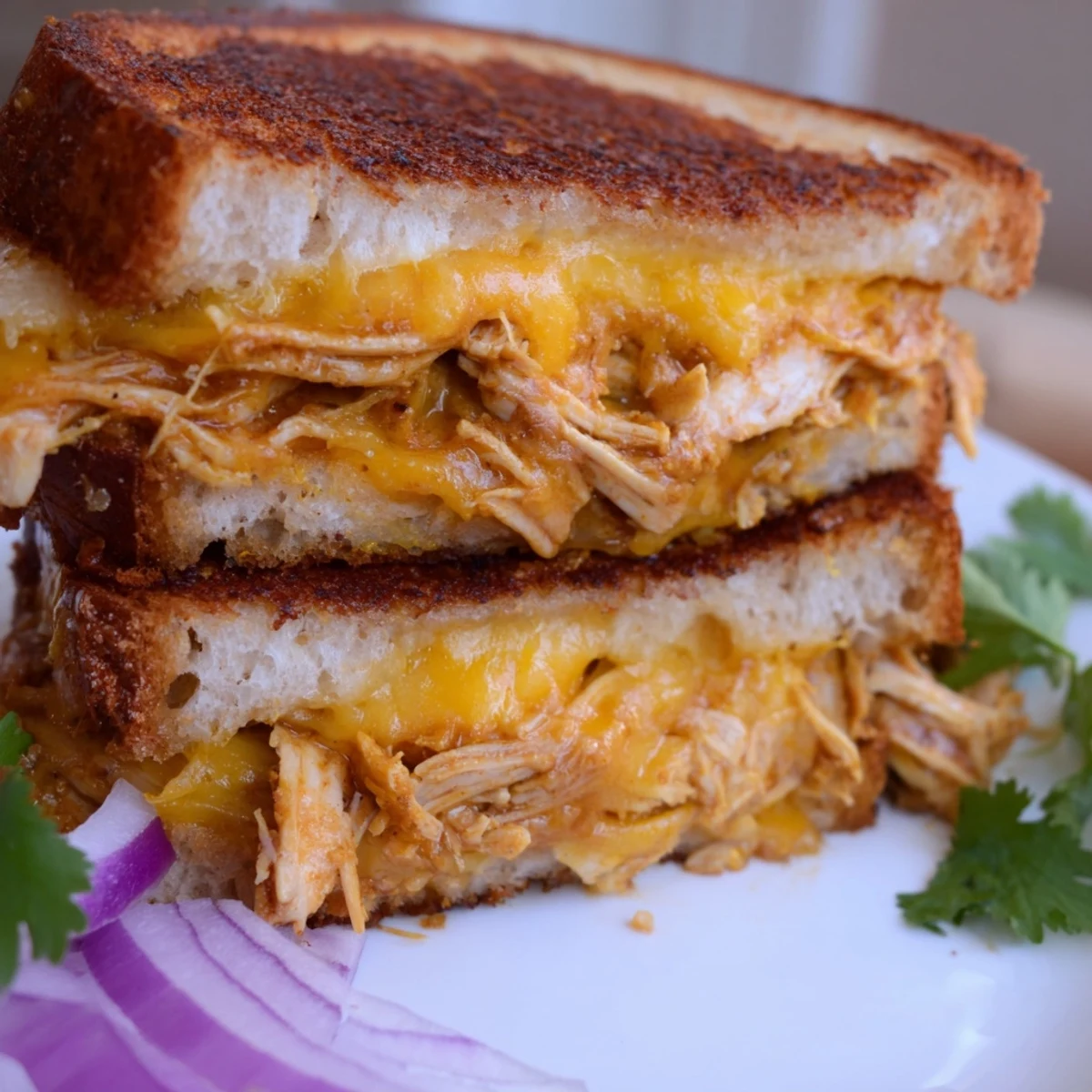 Golden BBQ chicken grilled cheese sandwich with melted cheddar and mozzarella cheese oozing from crispy buttered sourdough bread