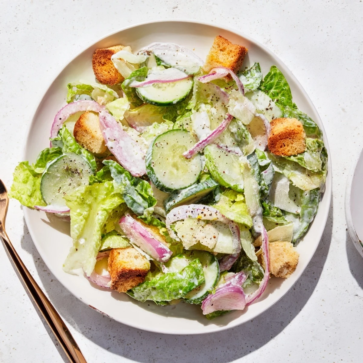 Refreshing cucumber Caesar salad featuring crisp vegetables, creamy dressing, and golden baked croutons on a rustic wooden table