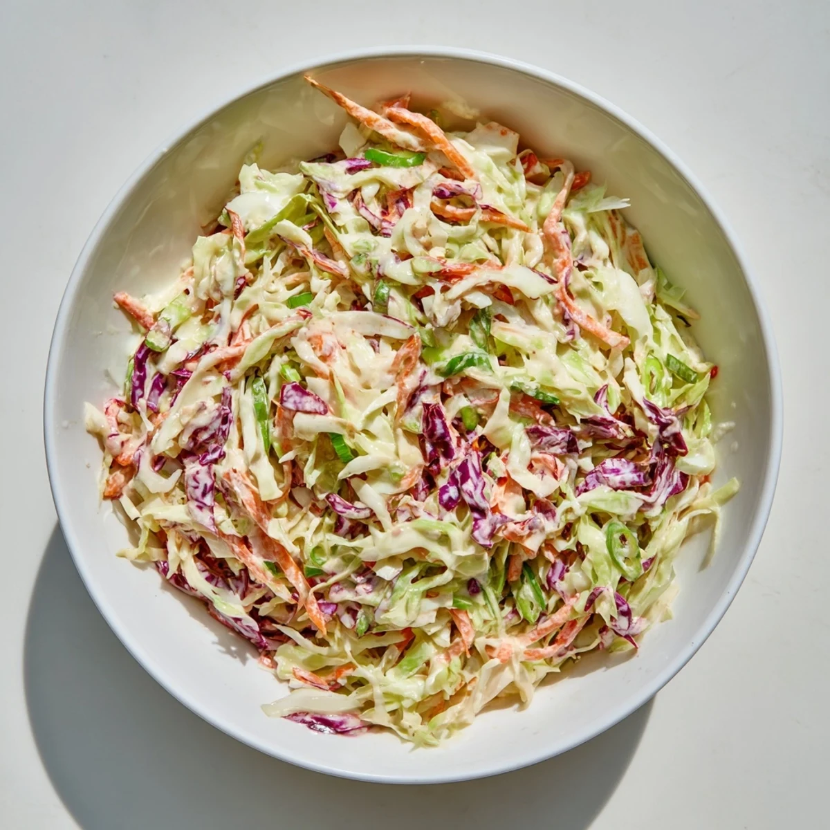 Creamy coleslaw featuring crisp green and red cabbage shreds coated in tangy white dressing.
