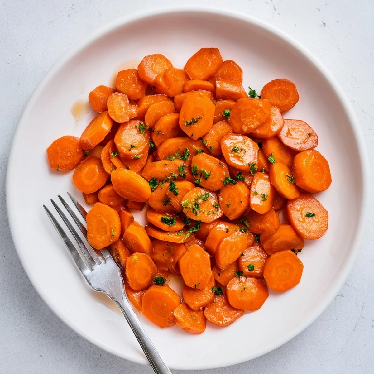 Tender brown sugar glazed carrots steaming in a cast iron skillet with melted butter