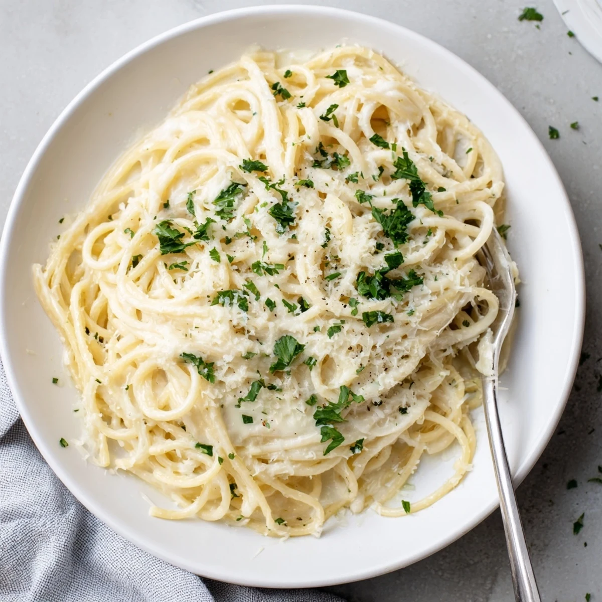 Creamy cheesy garlic Parmesan spaghetti dish plated with extra grated cheese topping and chopped parsley