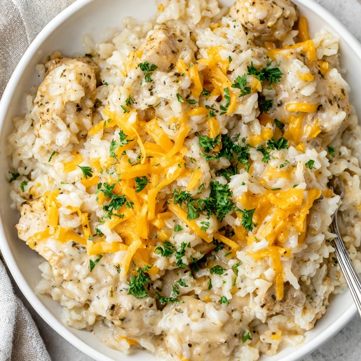 Tender chicken pieces atop fluffy white rice swimming in a savory cream sauce with melted cheese