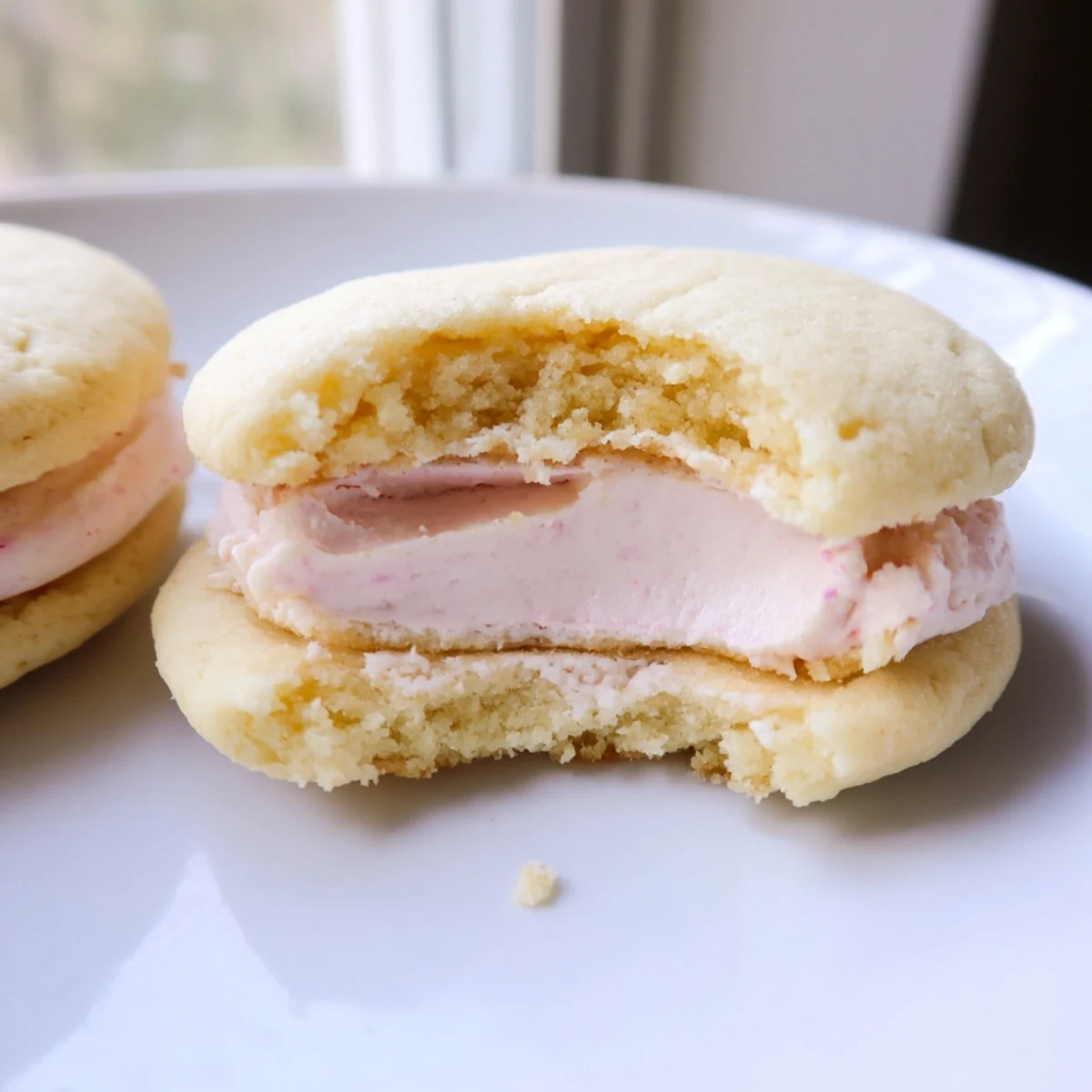 Delicate sugar cookie sandwiches showcasing layers of pink and lavender buttercream frosting