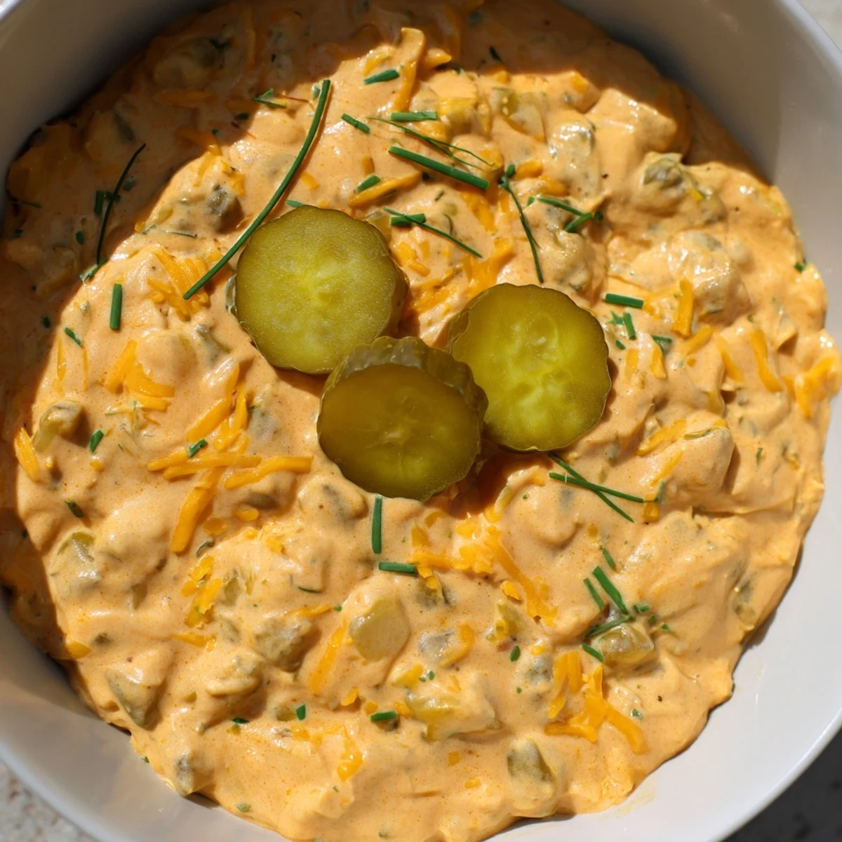 Tangy buffalo pickle dip topped with chopped chives and pickle slices ready for game day snacking