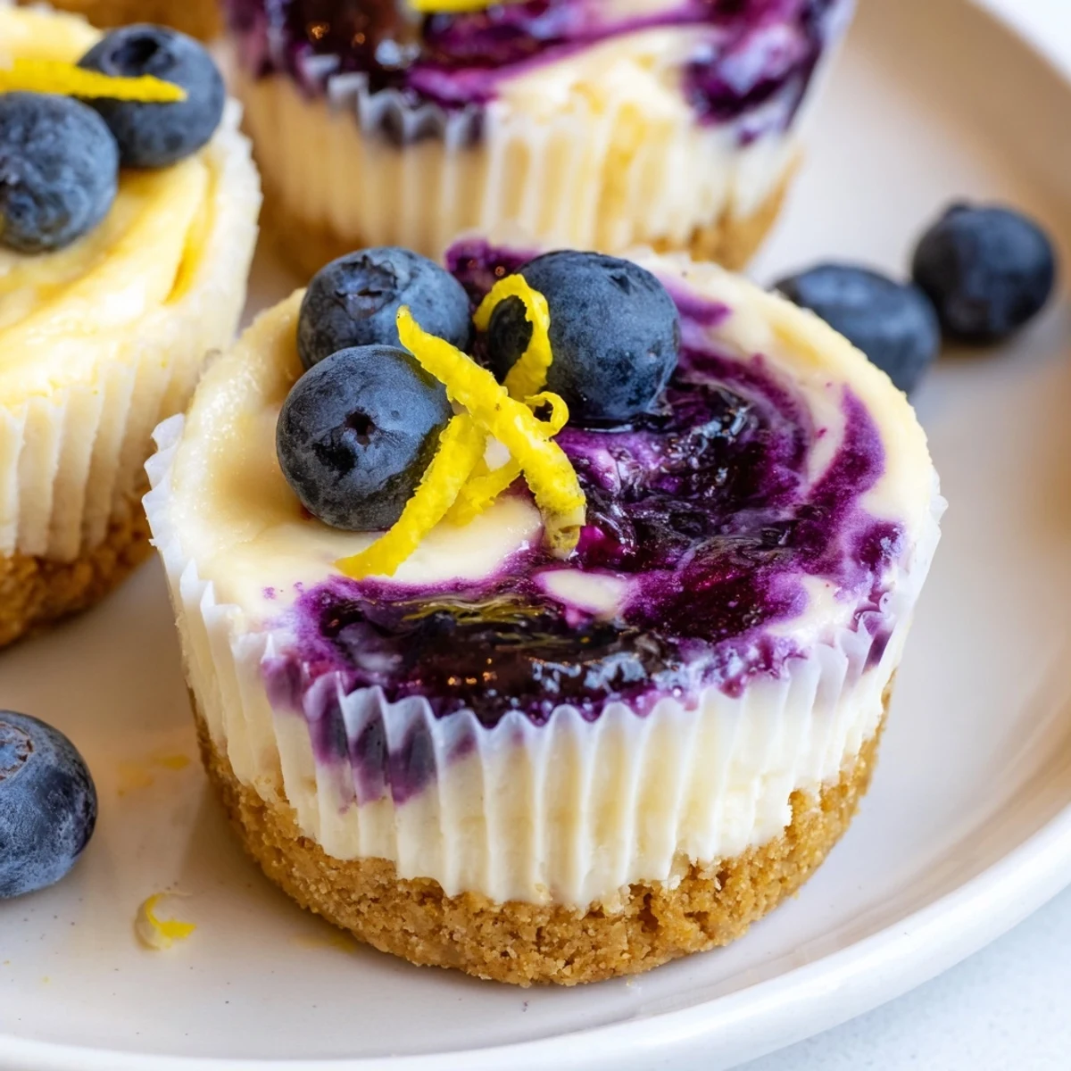 Bite-sized mini lemon blueberry cheesecakes garnished with fresh berries and bright lemon zest