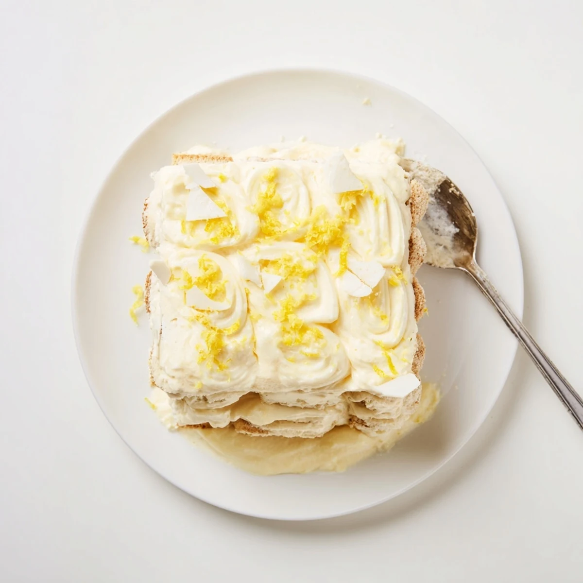 Layers of creamy lemon tiramisu topped with fresh zest in a glass dish.