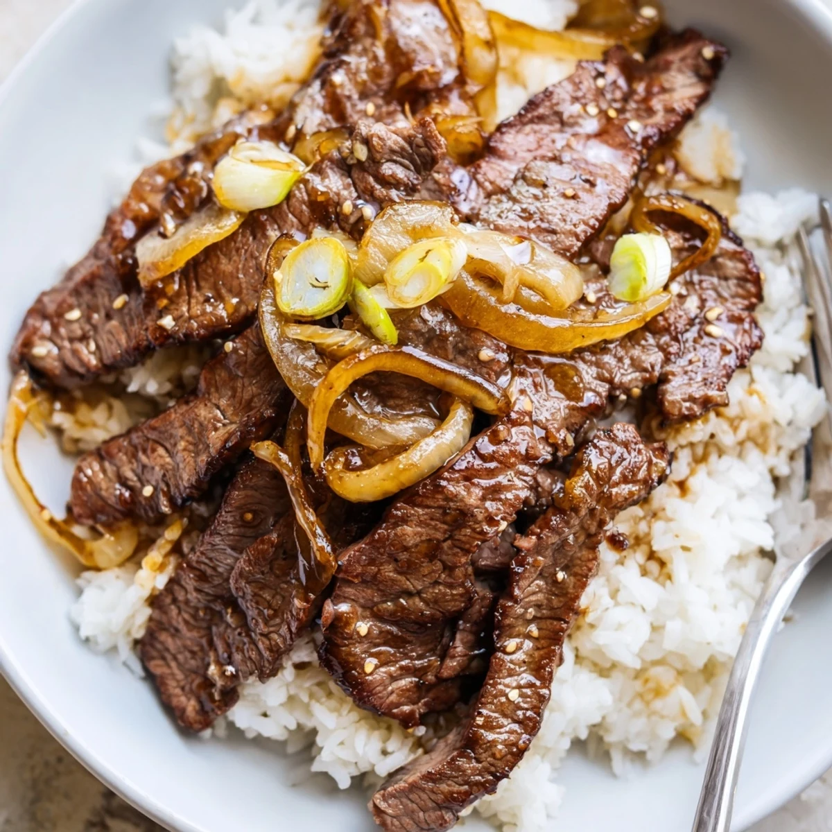Warm Crispy Beef and Onion Stir Fry piled over fluffy steamed jasmine rice  