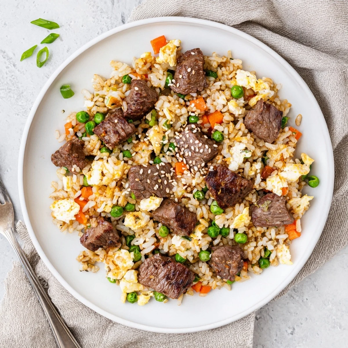 Savory Japanese fried rice with marinated steak, scrambled eggs, and peas freshly cooked on Blackstone