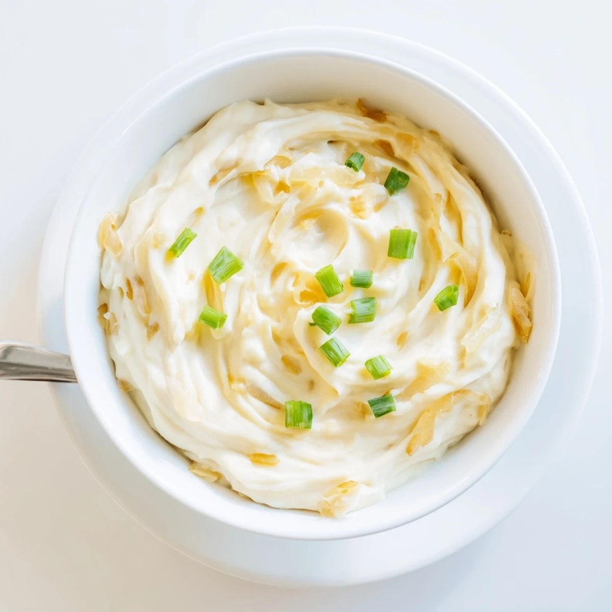 Creamy French onion dip topped with caramelized onions and fresh chives in a serving bowl