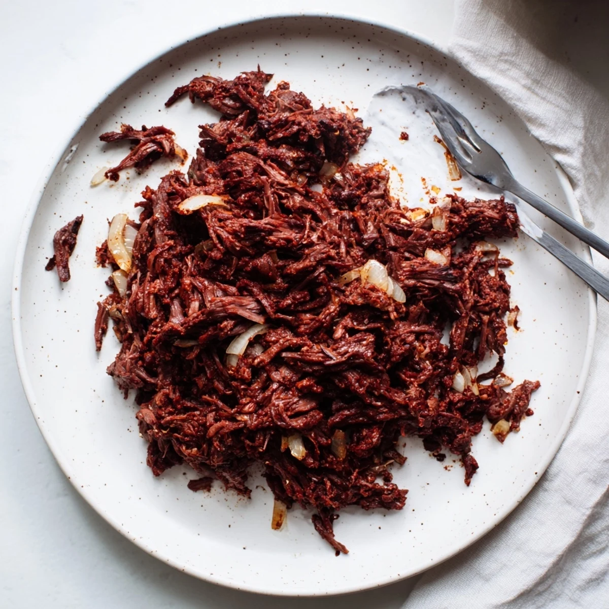 Tender Slow Cooker Beef Barbacoa shredded in a rich dark red chipotle sauce