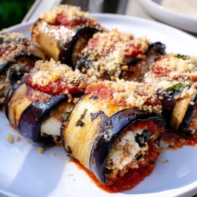 Tender roasted eggplant slices stuffed with creamy ricotta in Baked Eggplant Rollatini with Ricotta and Marinara, served alongside crusty bread.
