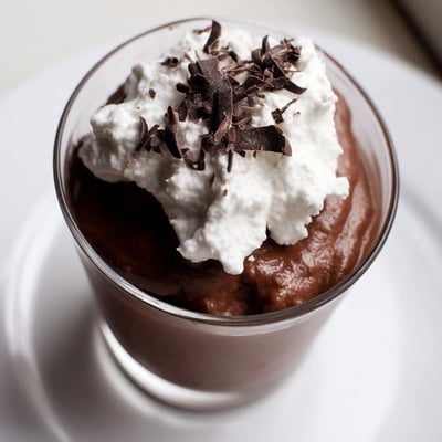 Silky vegan Chocolate Avocado Mousse served in a dessert glass with fresh berries and coconut flakes.