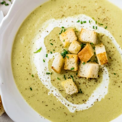 Creamy Broccoli Soup with Croutons served in a rustic bowl, featuring a velvety green texture and a drizzle of olive oil.