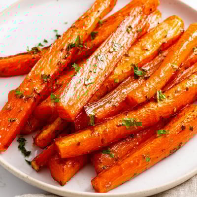 Herb-coated Roasted Carrot Sticks with Herbs on a rustic platter, paired with creamy dip for a savory side.